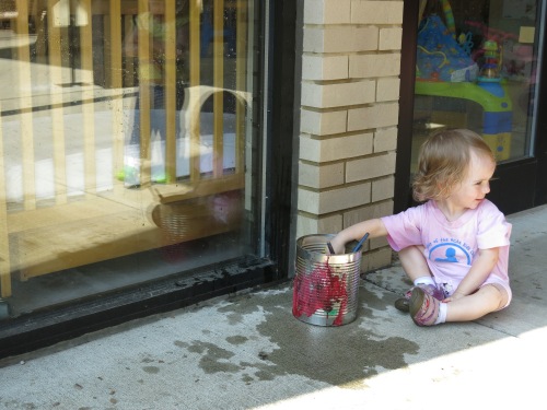Toddlers painting windows with water