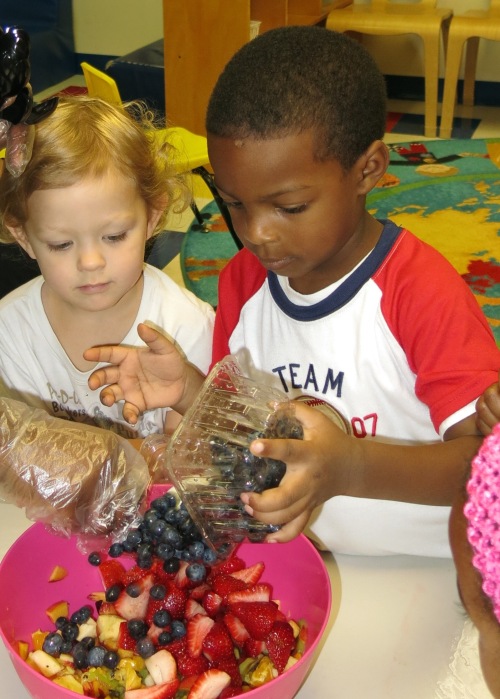 Day Nursery preschoolers adding blueberries to the fruit bowl