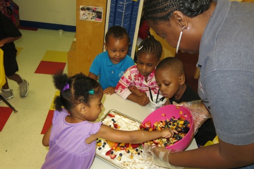 Day Nursery students spread the mixed fruit across the cream cheese base of their fruit pizza
